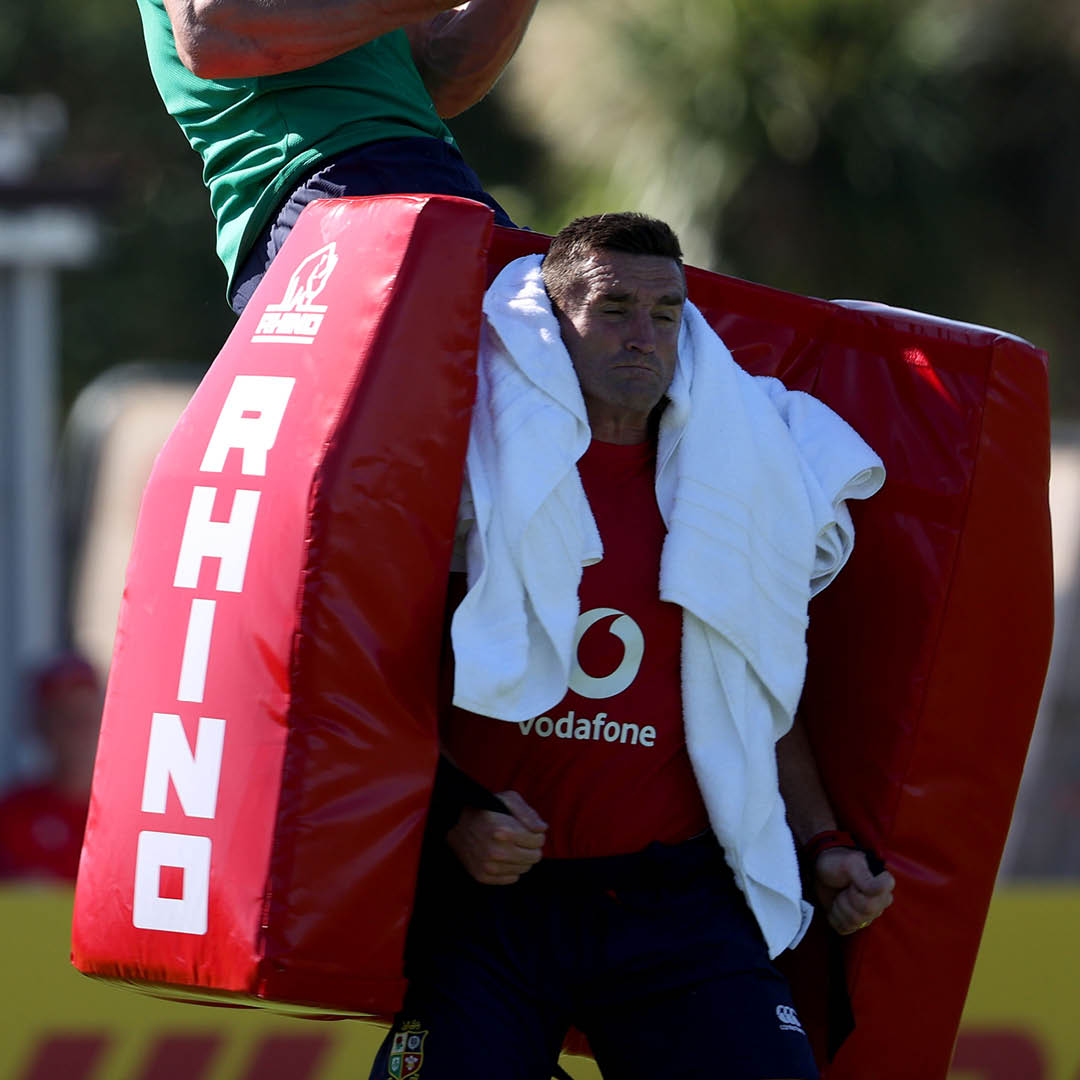 Two people practicing with a red Rhino Pro Climbing Bag, also known as a turtle bag, in a rugby setting.