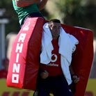 Two people practicing with a red Rhino Pro Climbing Bag, also known as a turtle bag, in a rugby setting.